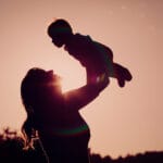 mother and little newborn daughter silhouettes at sunset